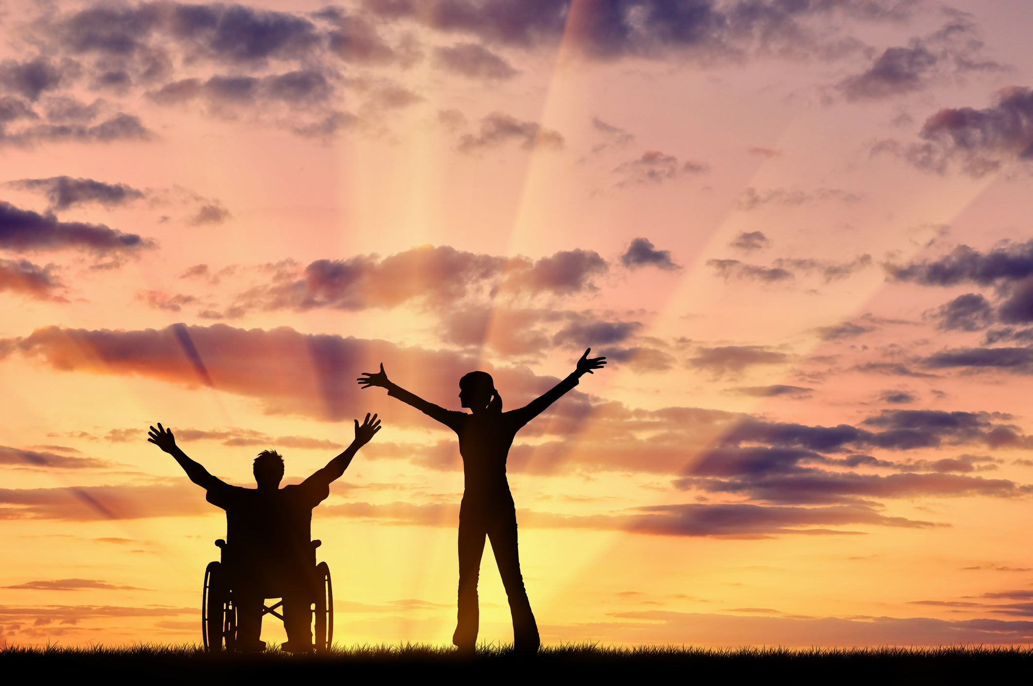 woman with man in wheelchair at sunset